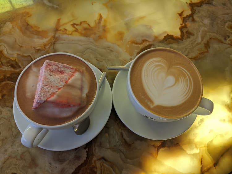 A fancy cup of coffee and holiday hot chocolate with an enormous peppermint marshmallow